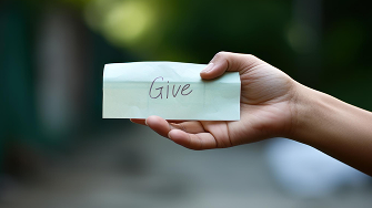 Hand holding a note with 'Give'